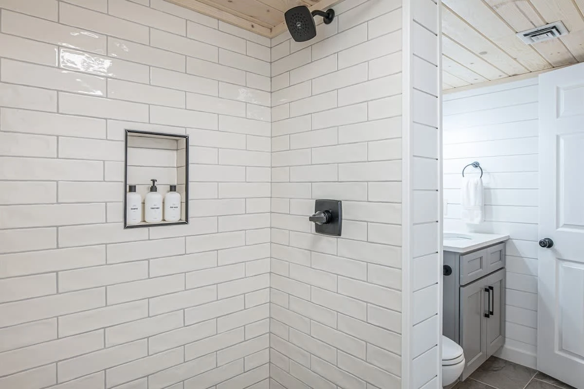 Bathroom features white-tiled walk-in shower