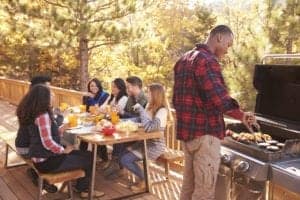 Friends enjoying a meal on the deck of a cabin.