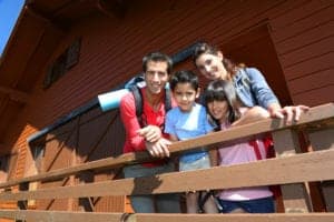 A family standing on the porch of their cabin.