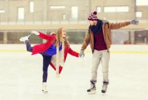 A young couple holding hands while ice skating.